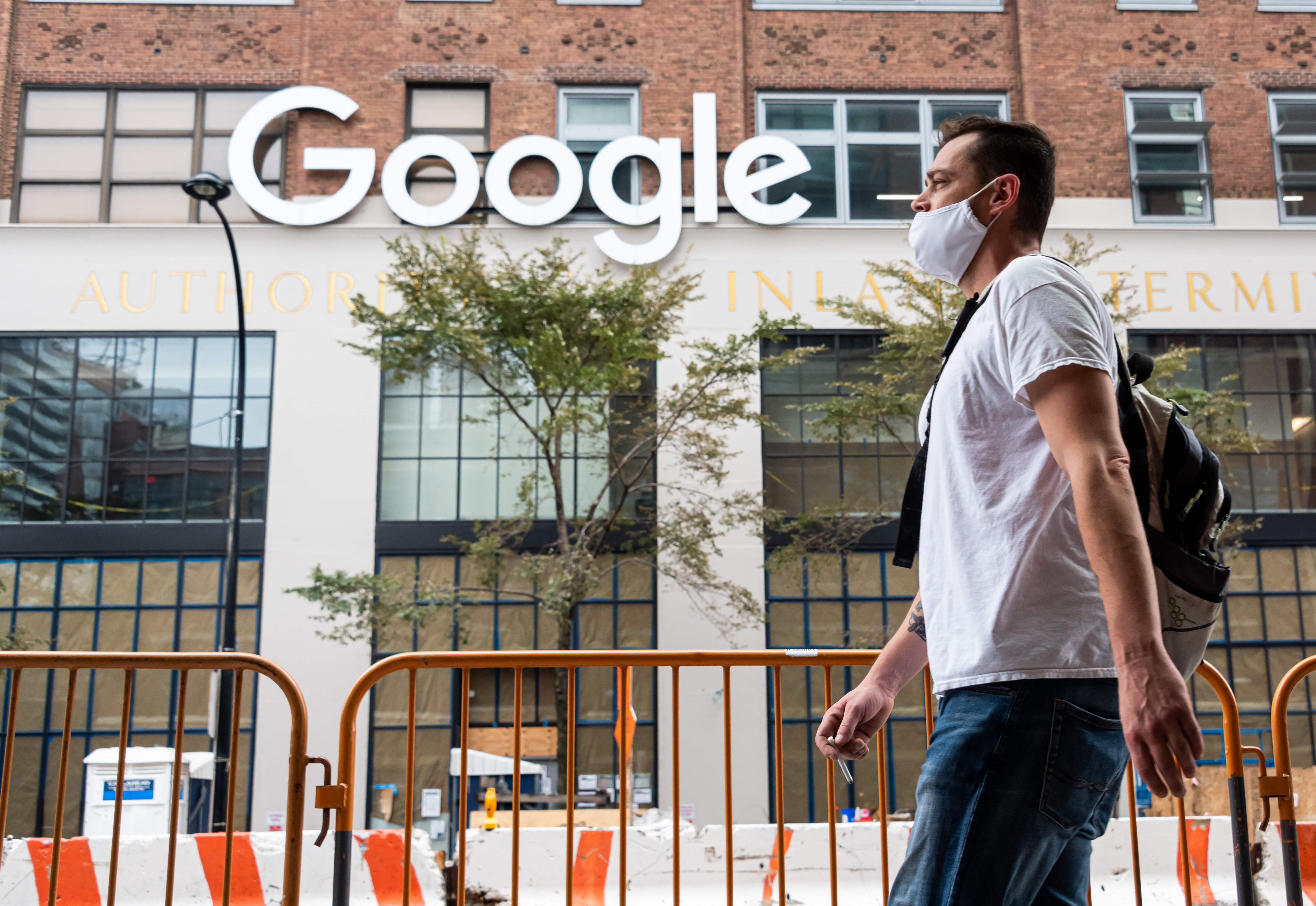 A masked man walks by Google's city HQ